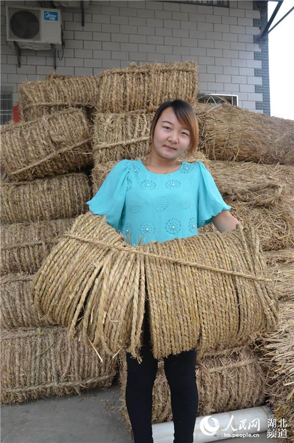 稻草加工戶曉月月為客商抱草繩上車。
